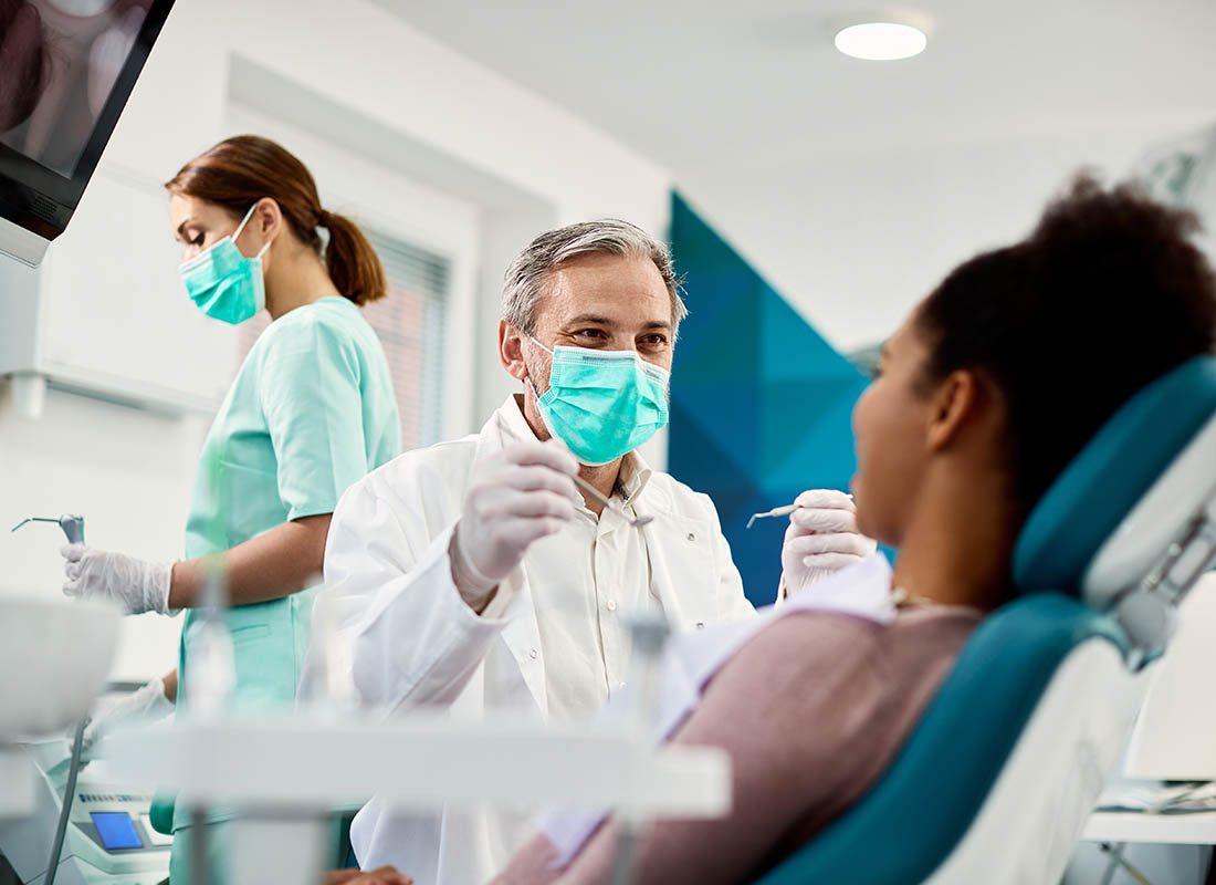 Group Dental Insurance - Woman Getting Her Teeth Cleaned by a Dentist and an Assistant